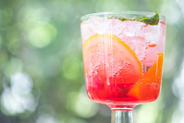 Pink and red fresh colorful exotic alcoholic cocktail with peach, orange and ice in the bar. Colorful pink soft drink with ice
