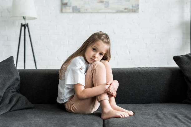 istock upset kid sitting on sofa and looking at camera at home 1167526535