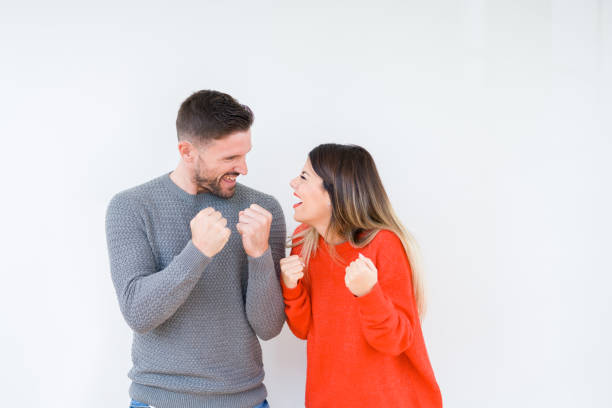 jeune beau couple togheter au-dessus du fond isolé très heureux et excité faisant le geste gagnant avec des bras levés, souriant et criant pour le succès. concept de célébration. - men sweater excitement satisfaction photos et images de collection