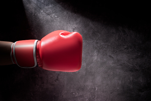 Hand with boxing gloves over black wall background