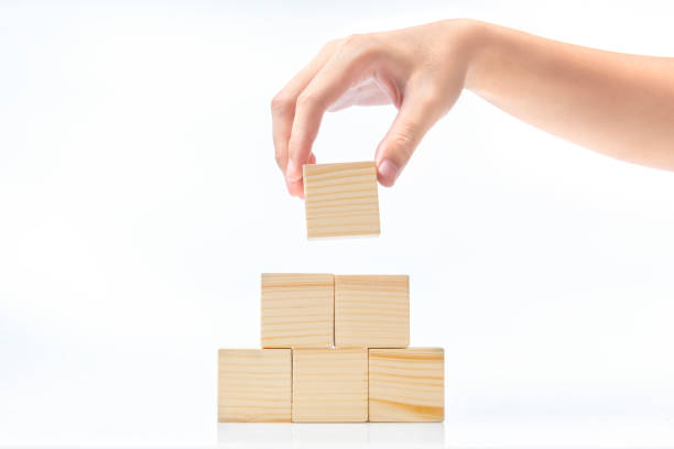 Hand build a pyramid from a wooden block Hand build a pyramid from a wooden block isolated over white background block cube pyramid built structure stock pictures, royalty-free photos & images