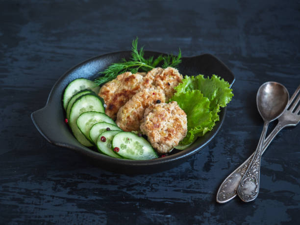 istock Breakfast of cutlets, lettuce and fresh cucumber on a black plate 1167532103