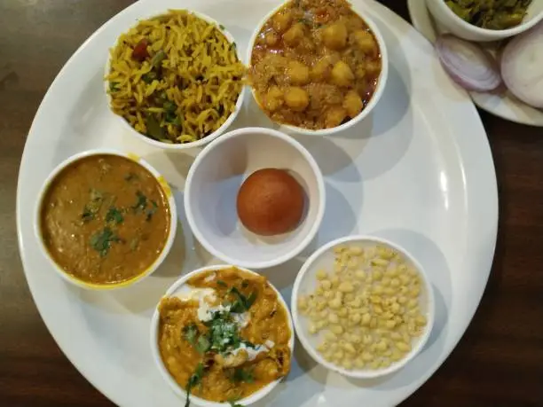 Indian thali has 3 spicy vegetable curry one fried rice and one sweet dish called Gulabjamun