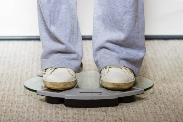 istock Person in tracksuit standing on weight machine 1167532271