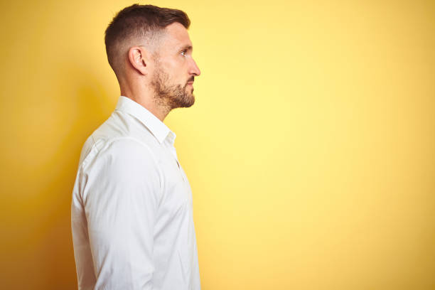 istock Young handsome man wearing elegant white shirt over yellow isolated background looking to side, relax profile pose with natural face with confident smile. 1167535523