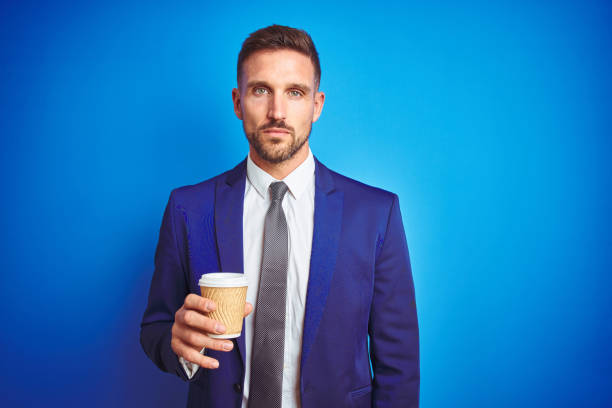 istock Young handsome business man drinking a coffee on a paper cup over blue isolated background with a confident expression on smart face thinking serious 1167536533