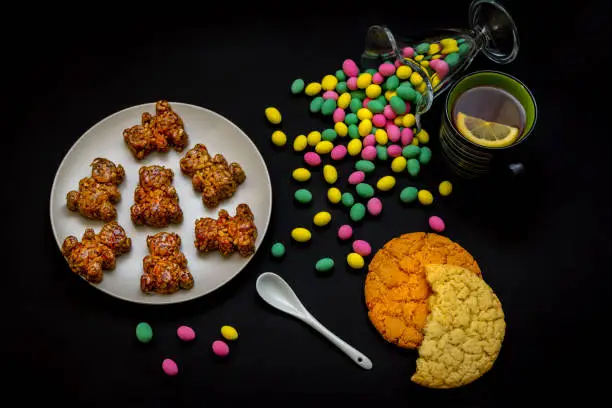 Photo of Homemade bear shape candies,glass vase with colorful candies and cup of tea
