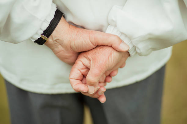 Hands Behind Their Back A close up shot of a senior man's hands behind his back, holding them together. hands behind back stock pictures, royalty-free photos & images