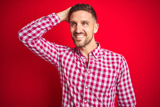 istock Young handsome man over red isolated background smiling confident touching hair with hand up gesture, posing attractive and fashionable 1167539614