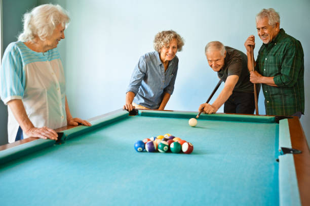 hombres y mujeres mayores jugando al billar en casa - pool hall fotografías e imágenes de stock