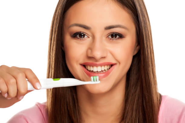 istock young woman brushing her teeth with electric tooth brush on white background 1167540626