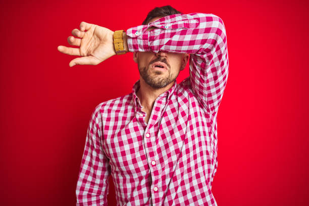 istock Young handsome man over red isolated background covering eyes with arm, looking serious and sad. Sightless, hiding and rejection concept 1167540741
