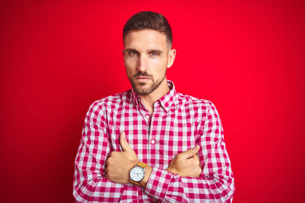istock Young handsome man over red isolated background skeptic and nervous, disapproving expression on face with crossed arms. Negative person. 1167540789