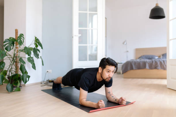 azjatycki człowiek robi ćwiczenia deskowania w domu - living room learning healthy lifestyle one person zdjęcia i obrazy z banku zdjęć
