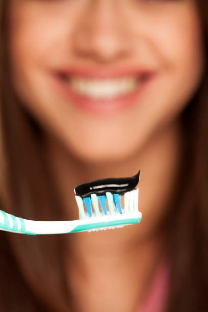 istock young woman holding tooth brush with black active charcoal toothpaste on white background 1167542694