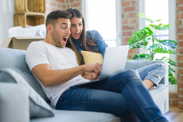 istock Young couple moving to a new home relaxing sitting on the sofa using computer laptop, smiling happy for moving to new apartment 1167543238