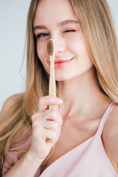 young beautiful girl holding a useful bamboo toothbrush - brushing teeth women toothbrush brushing imagens e fotografias de stock