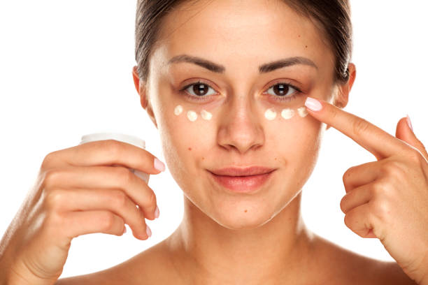 istock beautiful young woman applying moisturizer on her face on white background 1167544649