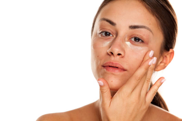 istock beautiful young woman applying moisturizer on her face on white background 1167544693