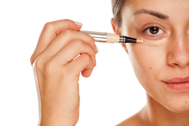 istock young beautiful girl applying concealer under her eyes on white background 1167544695