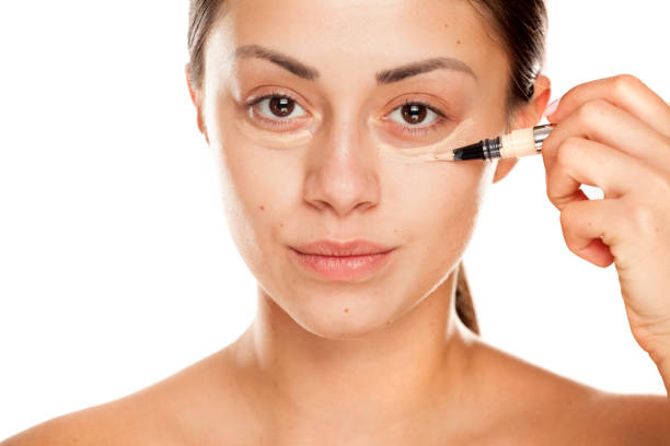 istock young beautiful girl applying concealer under her eyes on white background 1167545302