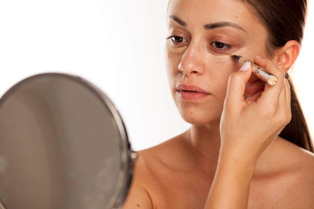 istock young beautiful girl applying concealer under her eyes on white background 1167545303