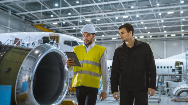 istock Team of Aircraft Maintenance Mechanics Moving through Hangar. Holding Tablet Computer 1167549579