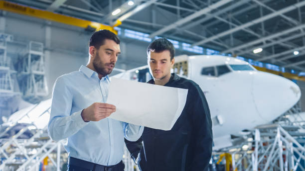 istock Aircraft Maintenance Worker and Engineer having Conversation. Holding Project Blueprint. 1167549614