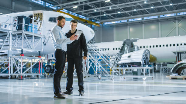 Aircraft Maintenance Worker and Engineer having Conversation. Holding Tablet. Aircraft Maintenance Worker and Engineer having Conversation. Holding Tablet. airplane maintenance stock pictures, royalty-free photos & images
