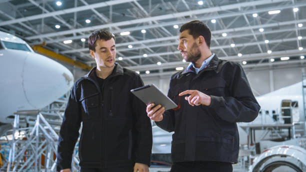 istock Team of Aircraft Maintenance Mechanics Moving through Hangar. Holding Tablet Computer 1167549625