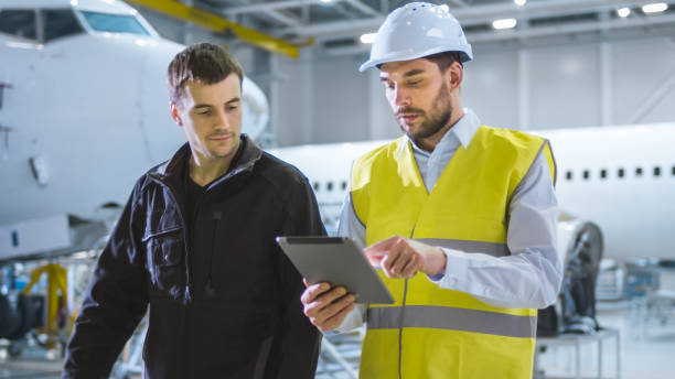 istock Team of Aircraft Maintenance Mechanics Moving through Hangar. Holding Tablet Computer 1167549634