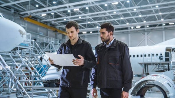istock Team of Aircraft Maintenance Mechanics Moving through Hangar. Holding Tablet Computer 1167549647