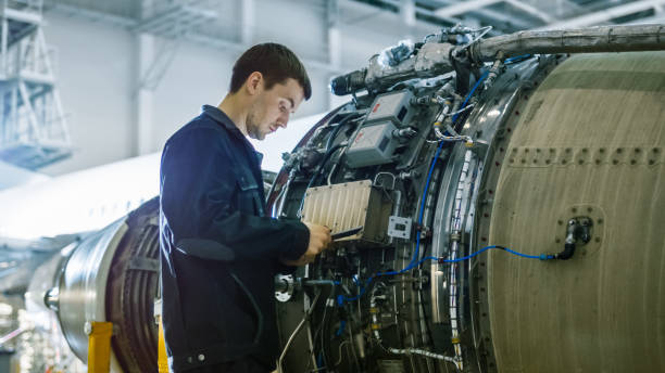 Aircraft Maintenance Mechanic Inspecting and Working on Airplane Jet Engine in Hangar Aircraft Maintenance Mechanic Inspecting and Working on Airplane Jet Engine in Hangar air vehicle stock pictures, royalty-free photos & images