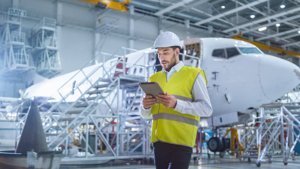 istock Aircraft Maintenance Mechanics Moving through Hangar. Holding Tablet Computer 1167549727