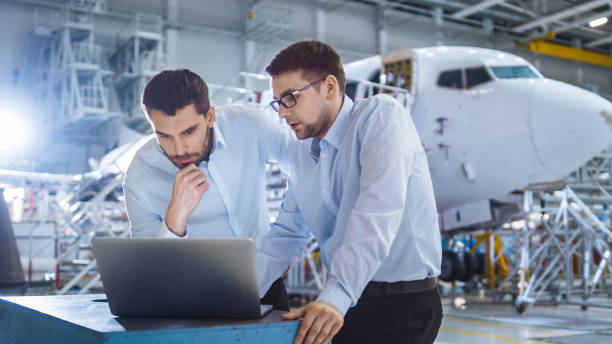 zwei flugzeuge mechanik arbeitet und dass gespräch neben laptop computer - luftfahrzeug stock-fotos und bilder