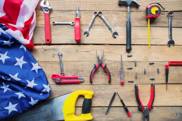 Top view of an American flag and handy tools shaping a text of Happy Labor Day on the wooden table