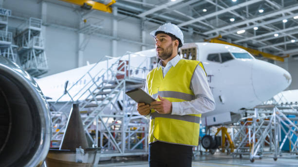 istock Aircraft Maintenance Mechanics Moving through Hangar. Holding Tablet Computer 1167550346