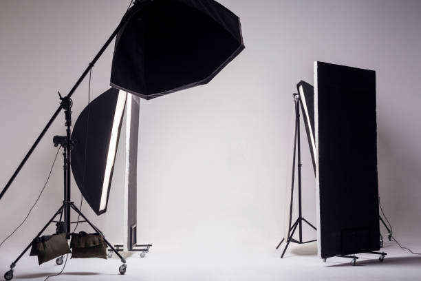 istock Professional photo studio with light setup included octagon softbox on boom, strip soft box and reflector on light gray background. 1167551648