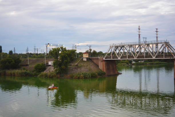 istock The gray Samara railway bridge over the surface of the Samara river with a beautiful landscape, green trees, bushes and greenery. Pictures of the river landscape with an unusual sky and bright clouds. Dnipro, Ukraine. 1167551998