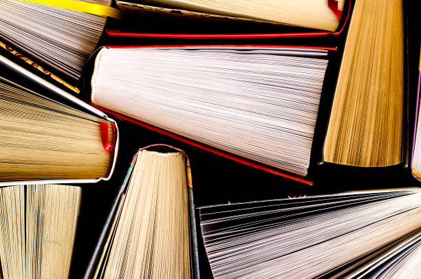 istock Lots of colourful thick open books stand on a dark background 1167556203