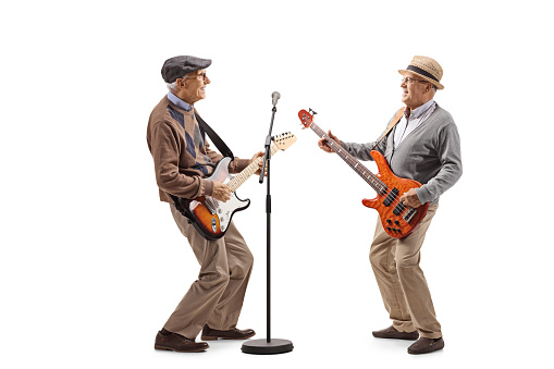Full length shot of two elderly men having a jam session with electric guitars isolated on white background