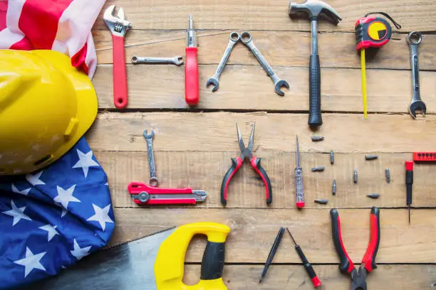 Top view of construction tools shaping Happy Labor Day text with American flag on the wooden table