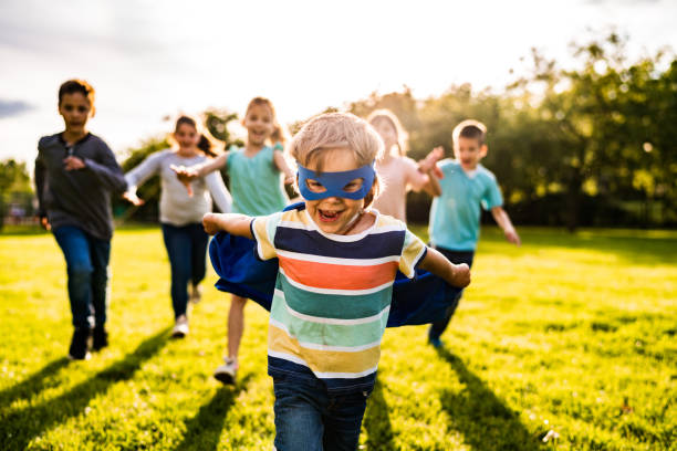 grupa dzieci biegających dla małego chłopca w masce - superhero child partnership teamwork zdjęcia i obrazy z banku zdjęć