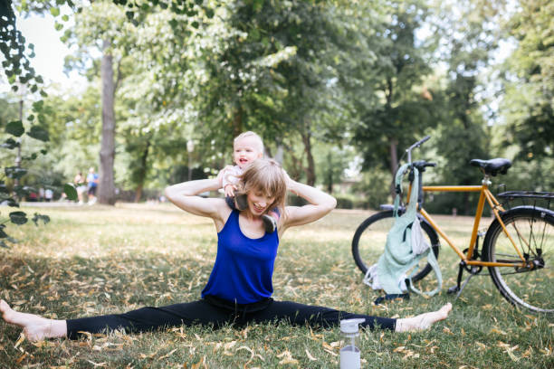 istock Young mother stretches while having fun with her baby in the public park 1167558330
