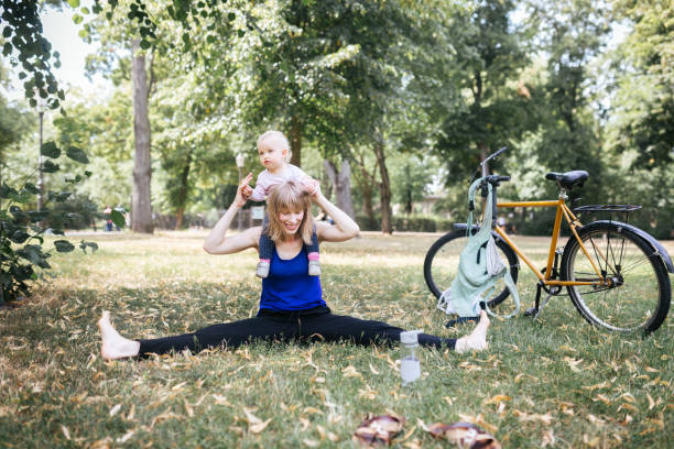 Young mother stretches while having fun with her baby in the public park