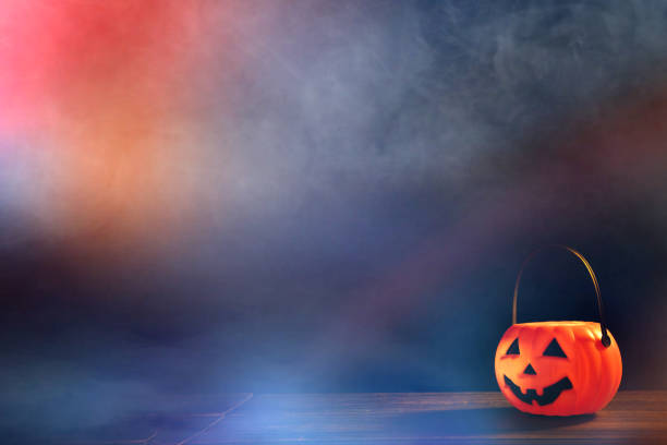 istock Halloween concept - Orange plastic pumpkin lantern on a dark wooden table with blurry sparkling light in the background, trick or treat. 1167558703