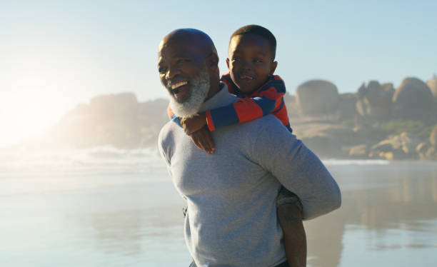 God couldn't be everywhere so he made grandparents Cropped shot of a happy senior man giving his cute grandson a piggyback ride on the beach grandson photos stock pictures, royalty-free photos & images