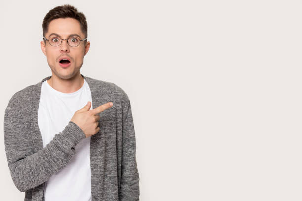 istock Amazed man open mouth makes big eyes point finger aside 1167560981