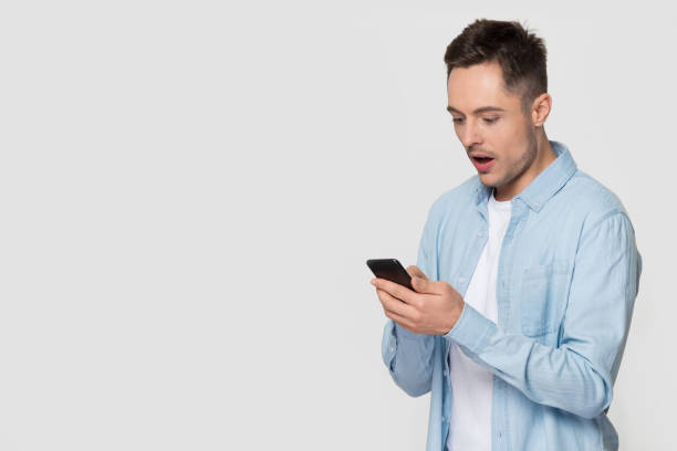 istock Amazed shocked man holding phone pose over studio grey background 1167560989