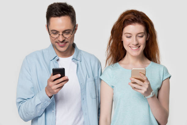 istock Millennial couple holding mobile phones standing on grey studio background 1167561031